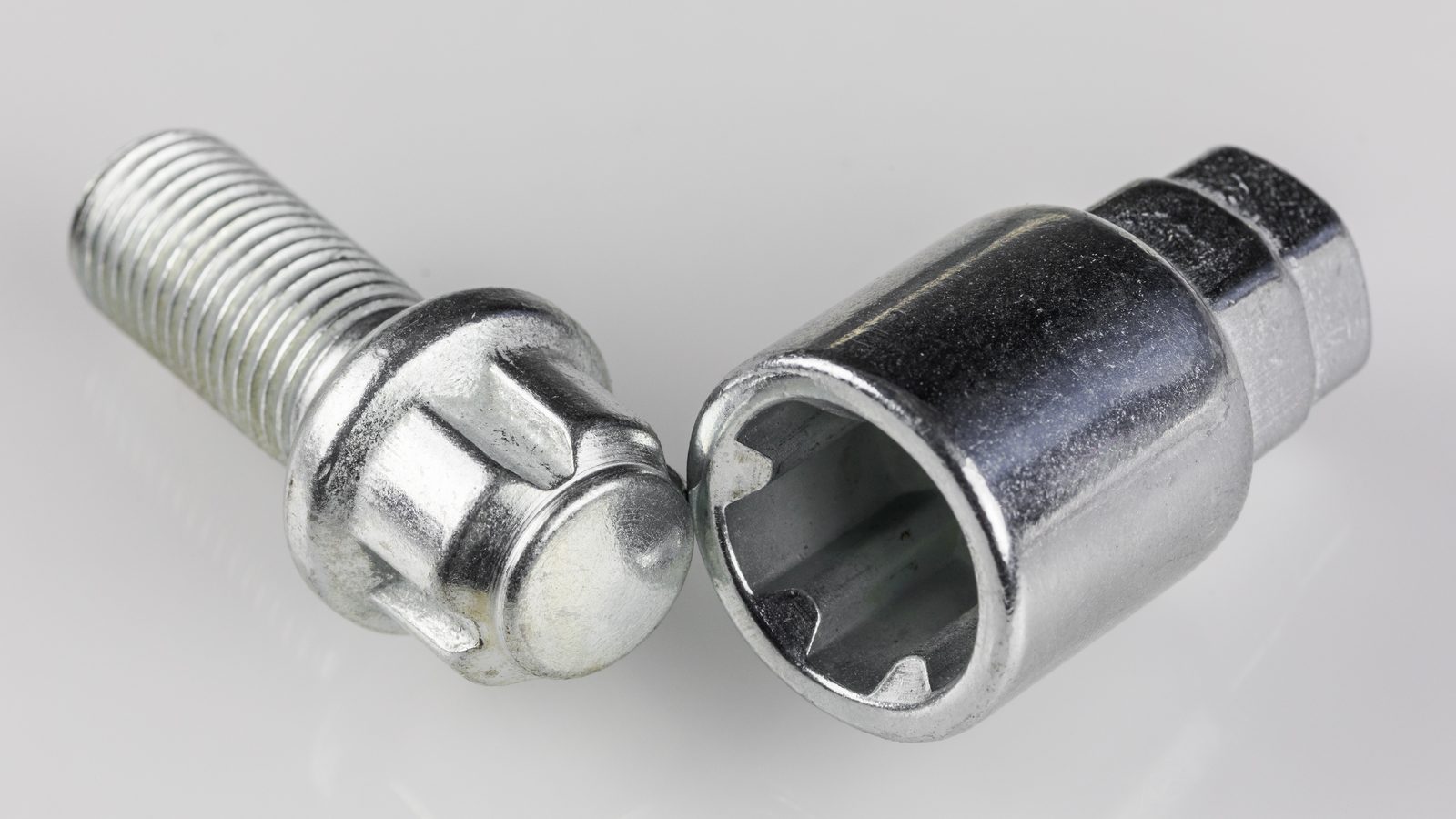 Photograph of a splined locking wheel bolt next to its matching key adapter socket